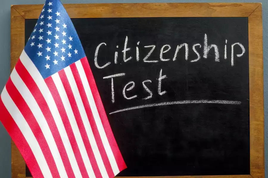 Citizenship test written on a chalk board with an American flag hanging beside